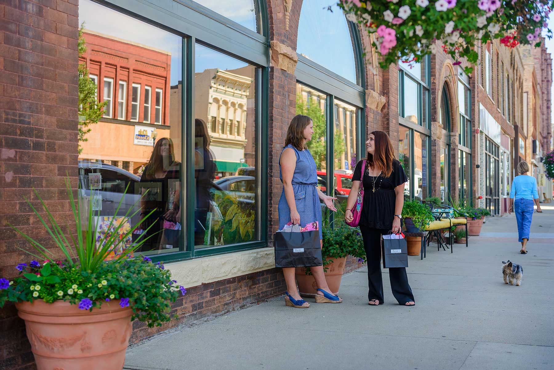 Women carrying shopping bags and chatting in downtown Watertown