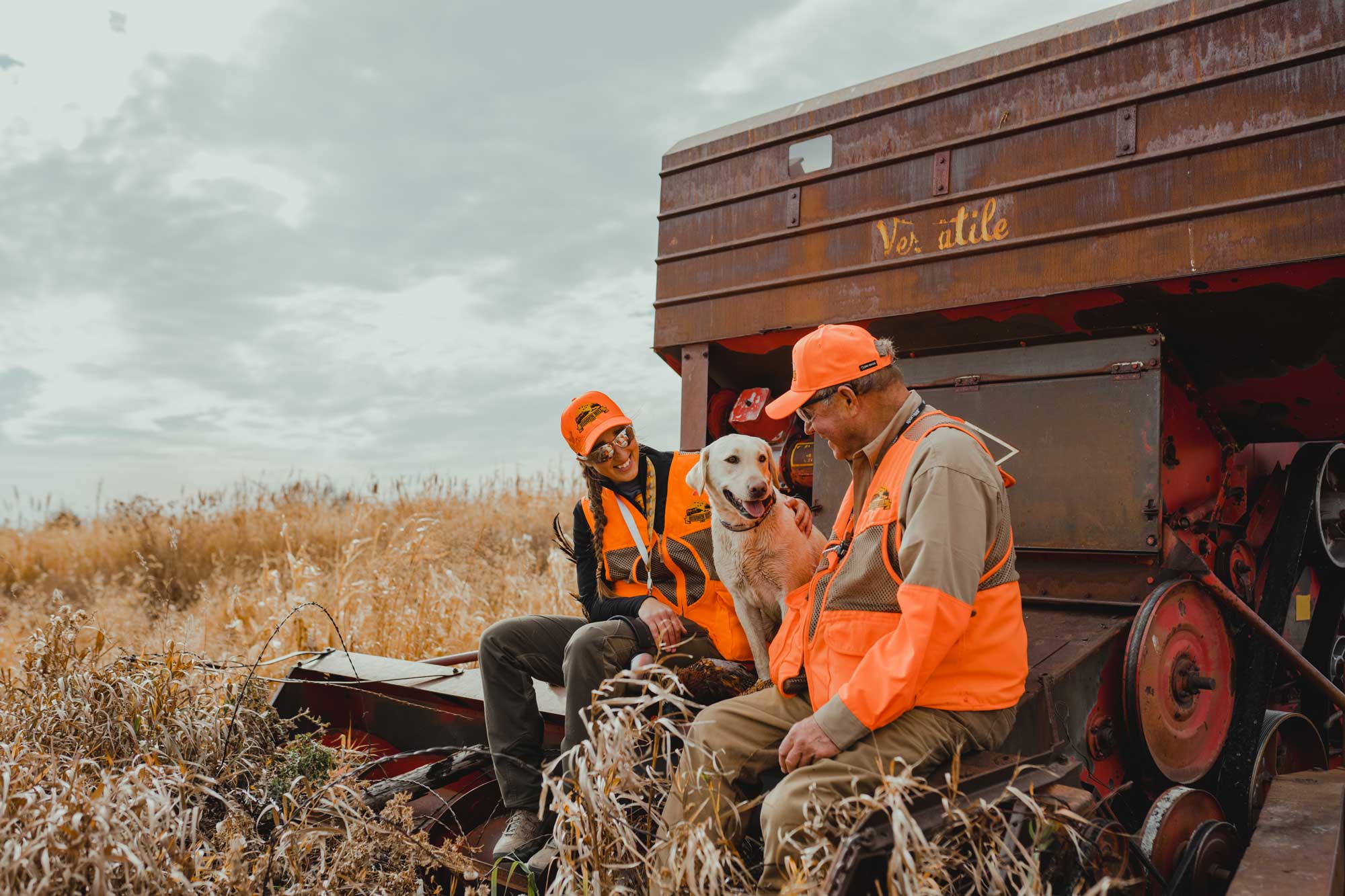 Pheasant hunters and dog sitting on farm equipment