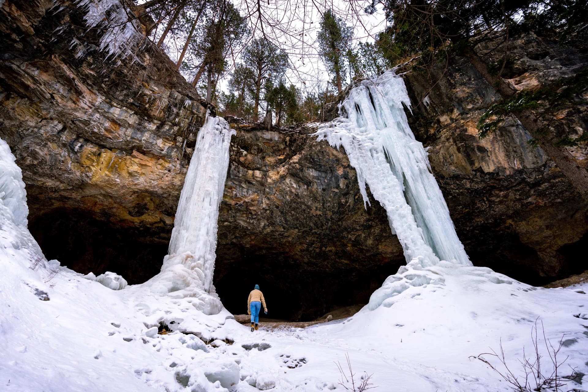 A woman walks toward a frozen waterfall at Community Caves in Spearfish Canyon, South Dakota