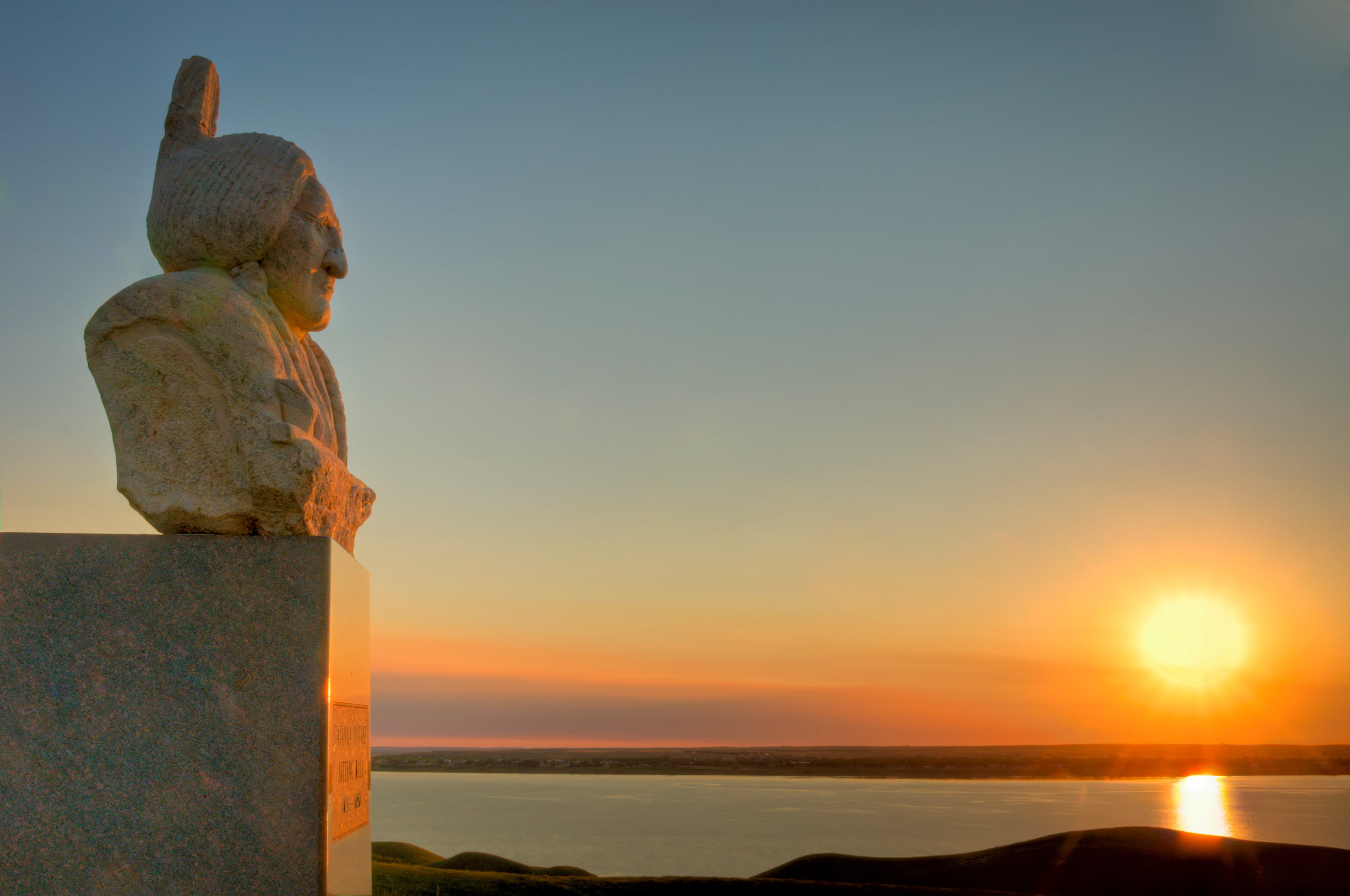 The Monument to Sitting Bull, a bust of the Lakota leader, is pictured amid a scenic sunset