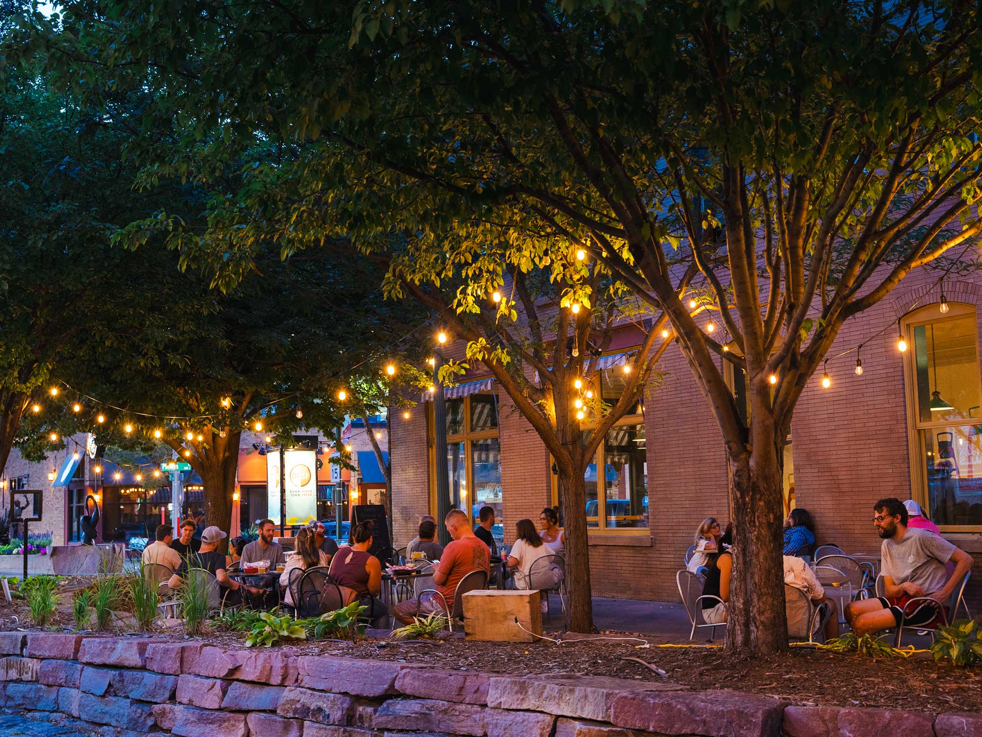 People drinking on a patio under string lights at Fernson Downtown, a brewery in Sioux Falls, South Dakota.
