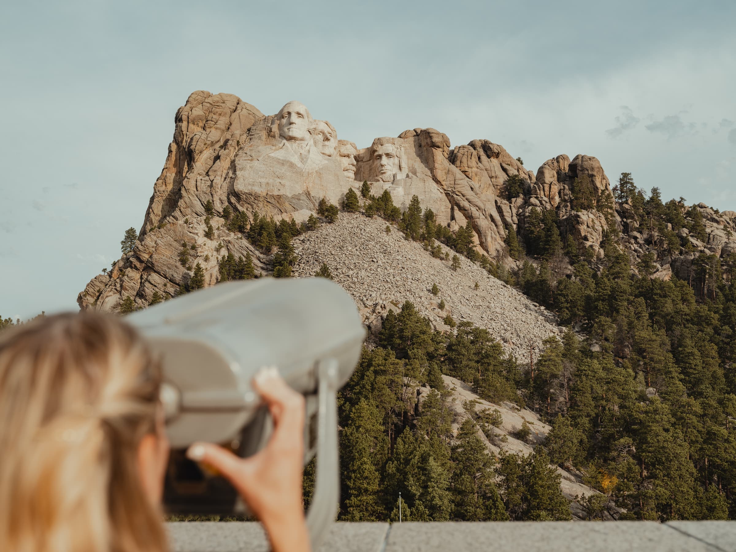 A woman uses a viewfinder to view Mount Rushmore National Memorial. Keystone, South Dakota.
