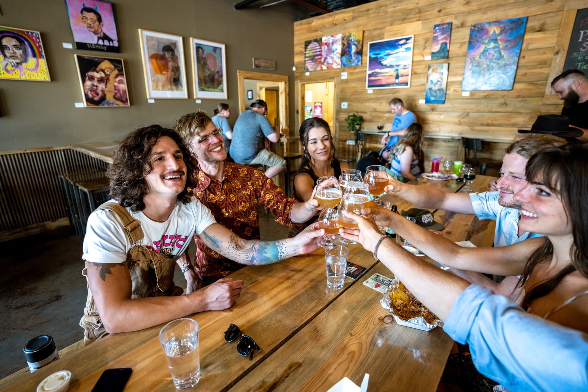 A group of friends clink and cheers with glasses of refreshing beer at Lost Cabin Beer Co. in Rapid City, SD.