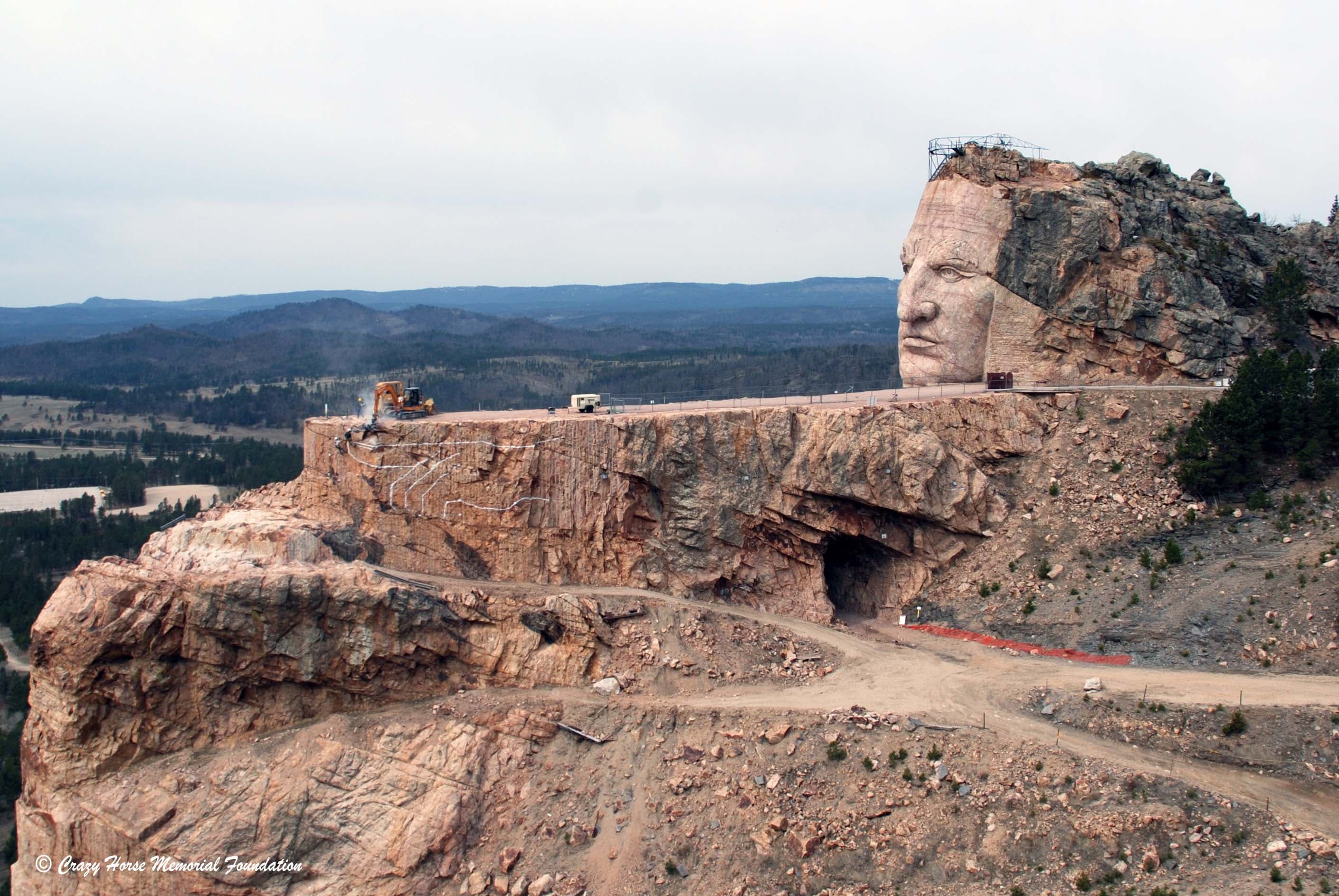 The Crazy Horse National Monument face is overlooking a out over a rocky landscape speckled with evergreen trees