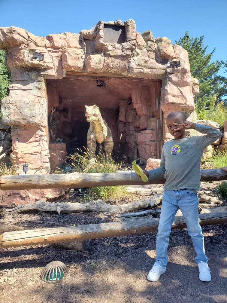 Tariq the "Corn Kid" posing with a dinosaur exhibit