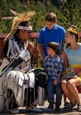 Native American Tribal dancer talking with tourist family