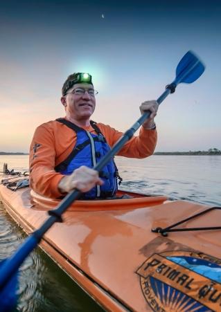 Man with headlamp kayaking on river