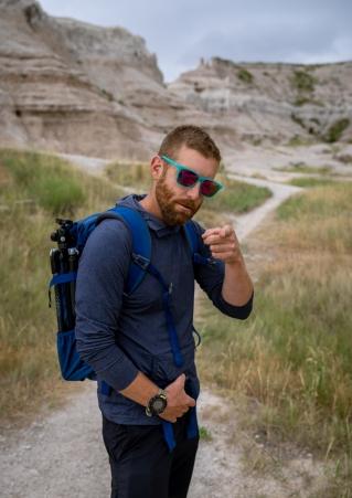 Man in sunglasses pointing at camera in Badlands