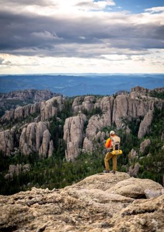 A man with a backpack stands overlooking the rock formations in Custer State Park