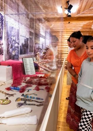 Two people look upon a collection of Native American crafts