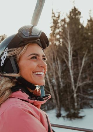 Female Skier looking happy riding the ski lift as the sun starts to set on Terry Peak Ski Area in the Black Hills of South Dakota
