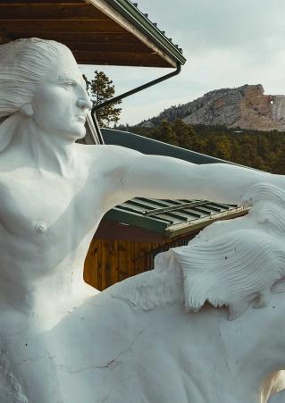 A distant view of Crazy Horse Memorial with a smaller model of the sculpture in the foreground. Crazy Horse, South Dakota.