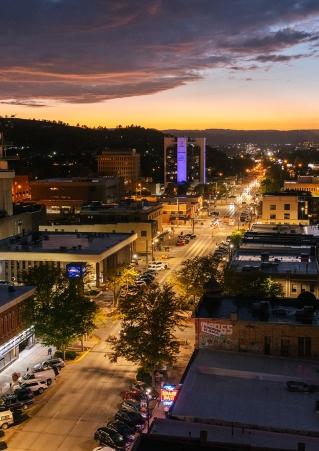 An aerial view of Rapid City at night, lit by warm streetlights and vehicle headlights.