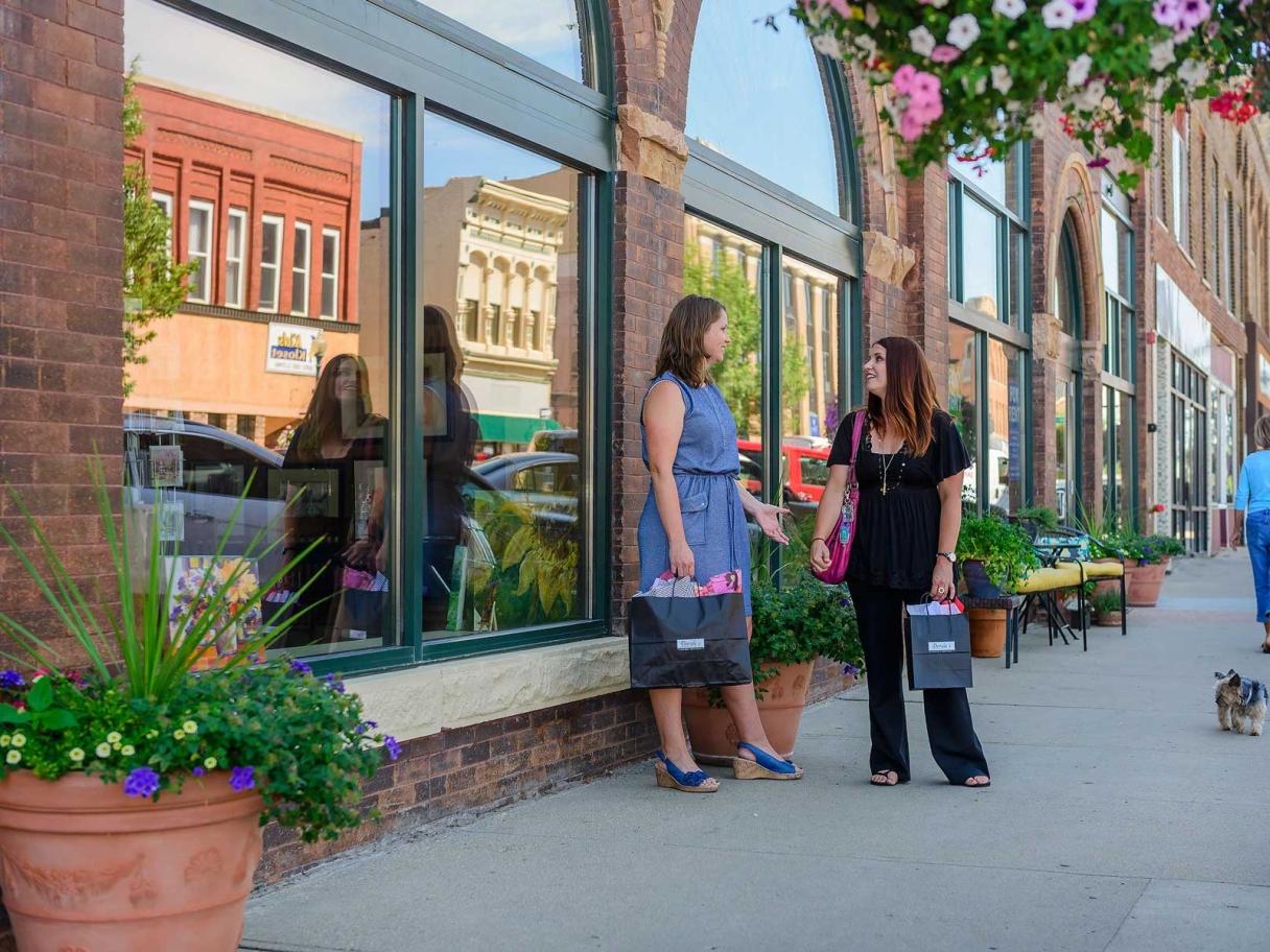 Women carrying shopping bags and chatting in downtown Watertown