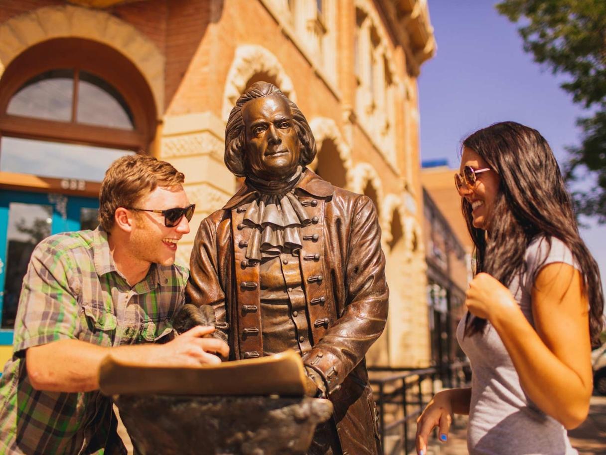 Two people interacting with City of Presidents statue
