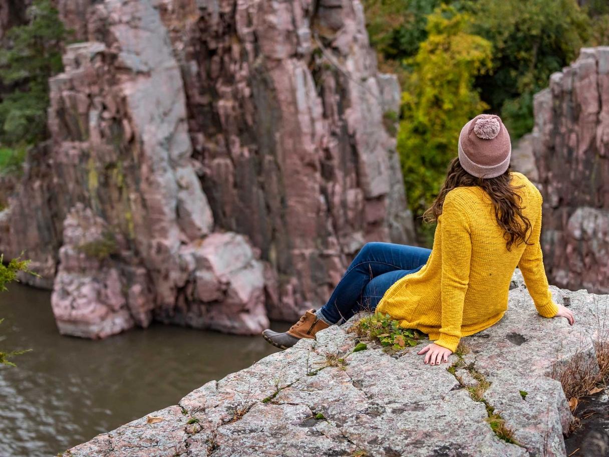 Woman sitting on river overlook in fall