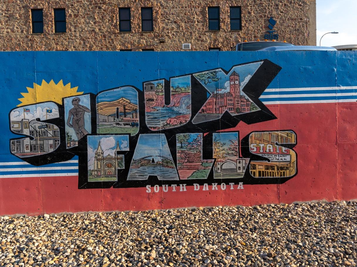 A mural on a wall in Sioux Falls, South Dakota, with each letter displaying a key location in the city against a blue and red background.