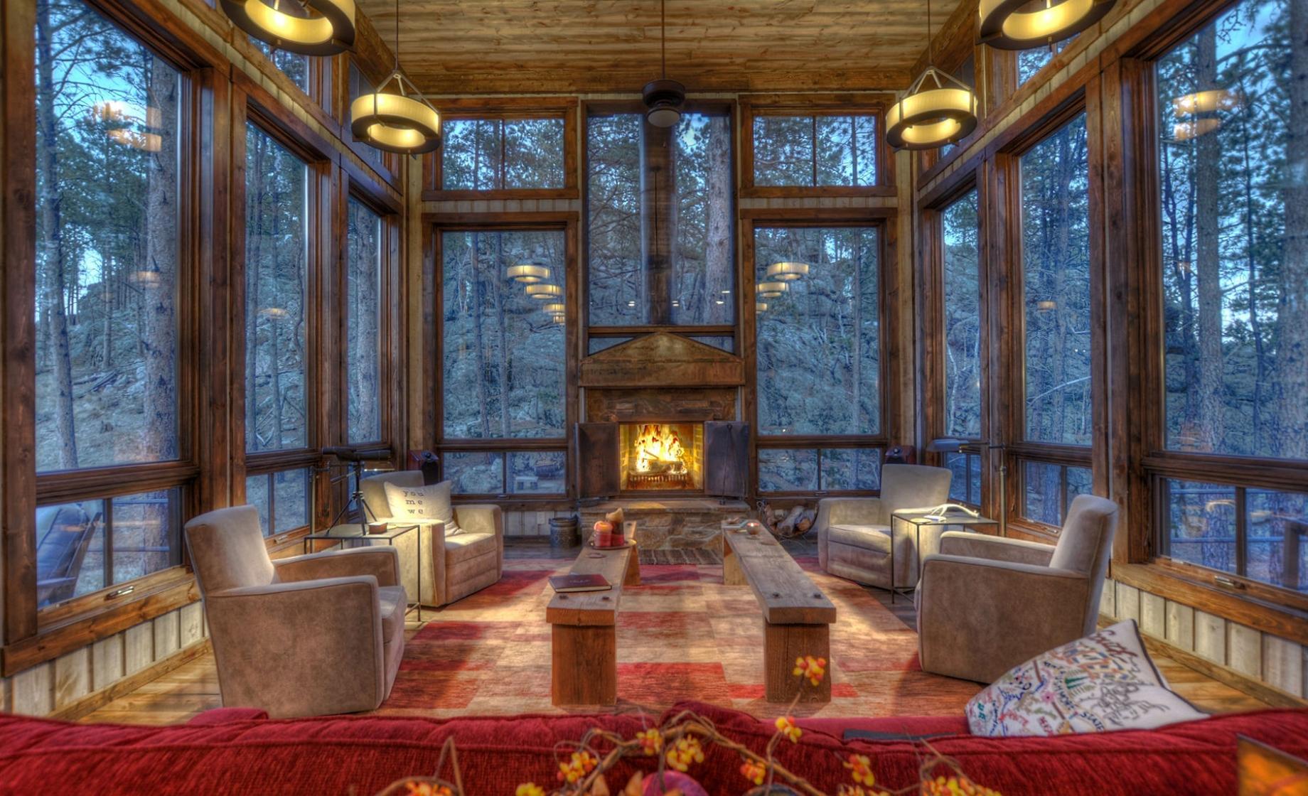 Interior view of Glass Lodge, a cabin rental near Keystone, South Dakota, with floor-to-ceiling windows on all sides that overlook the Black Hills National Forest.