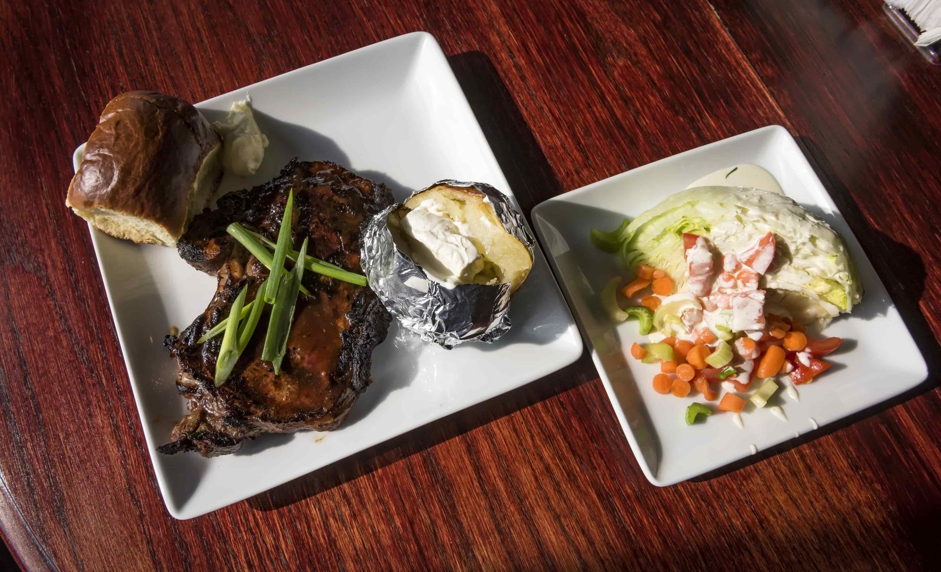Steak, potato, bun, salad and more on plates