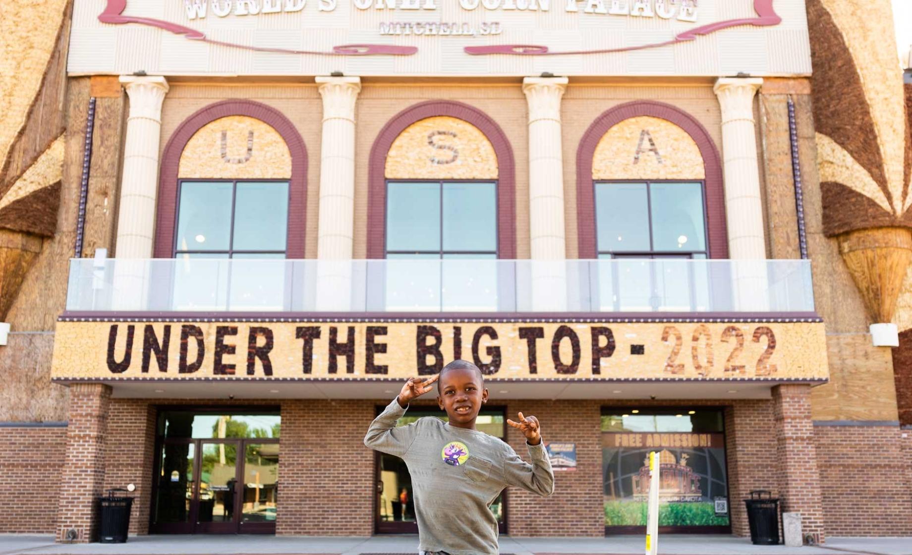 Tariq the "Corn Kid" posing with peace signs in front of the Corn Palace