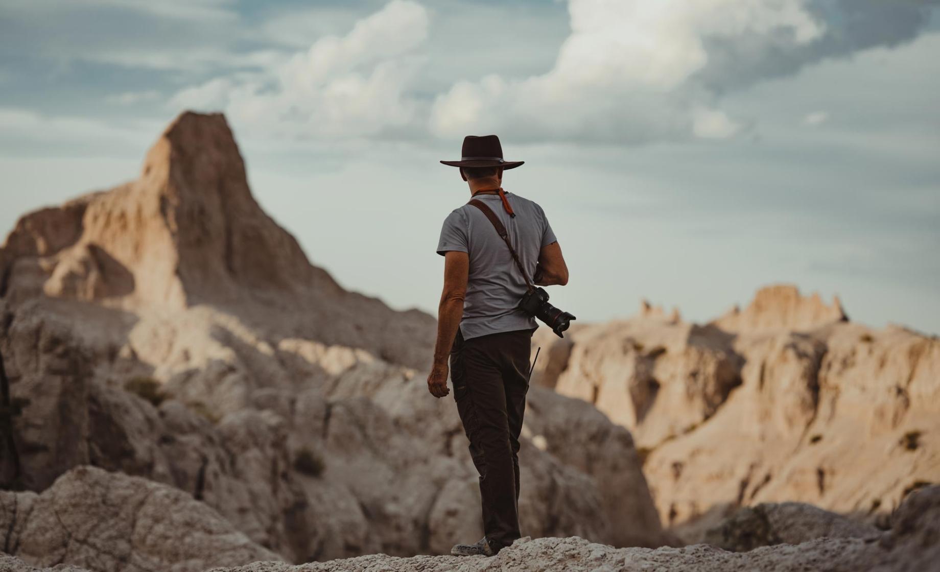 Man with a camera slung over his shoulder looking out over Badlands National Park