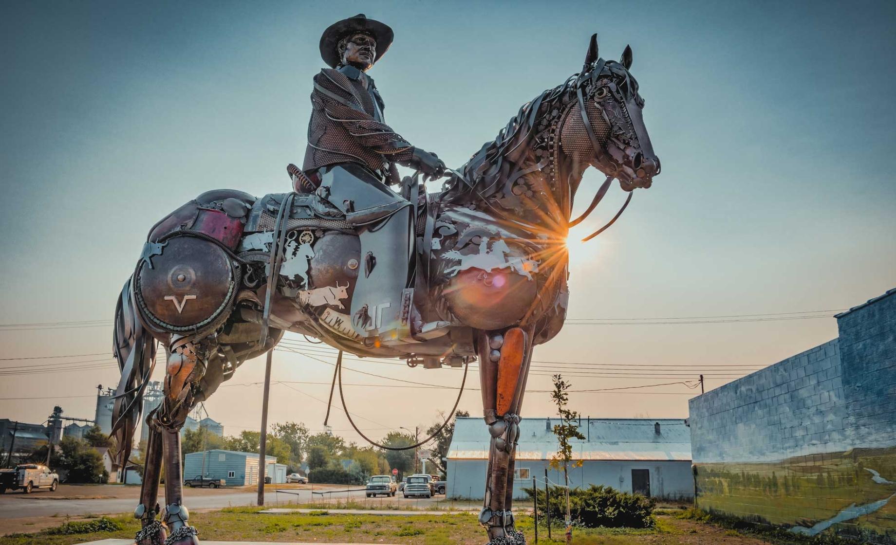Scrap metal sculpture of a cowboy on horseback at sundown