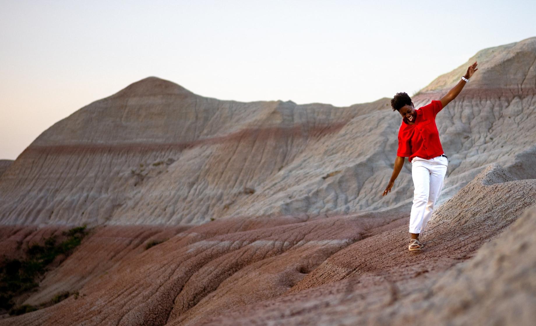 A person walks with joyful outstretched arms along a hill in Badlands National Park