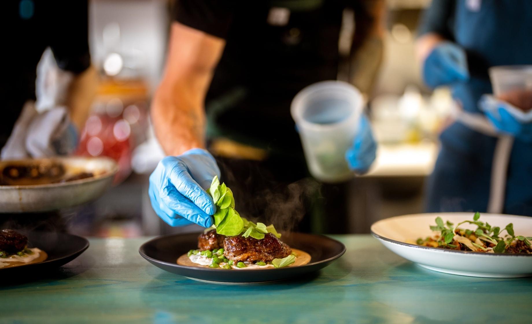 A chef places ruffage on top of a meal at Skogen Kitchen in Custer