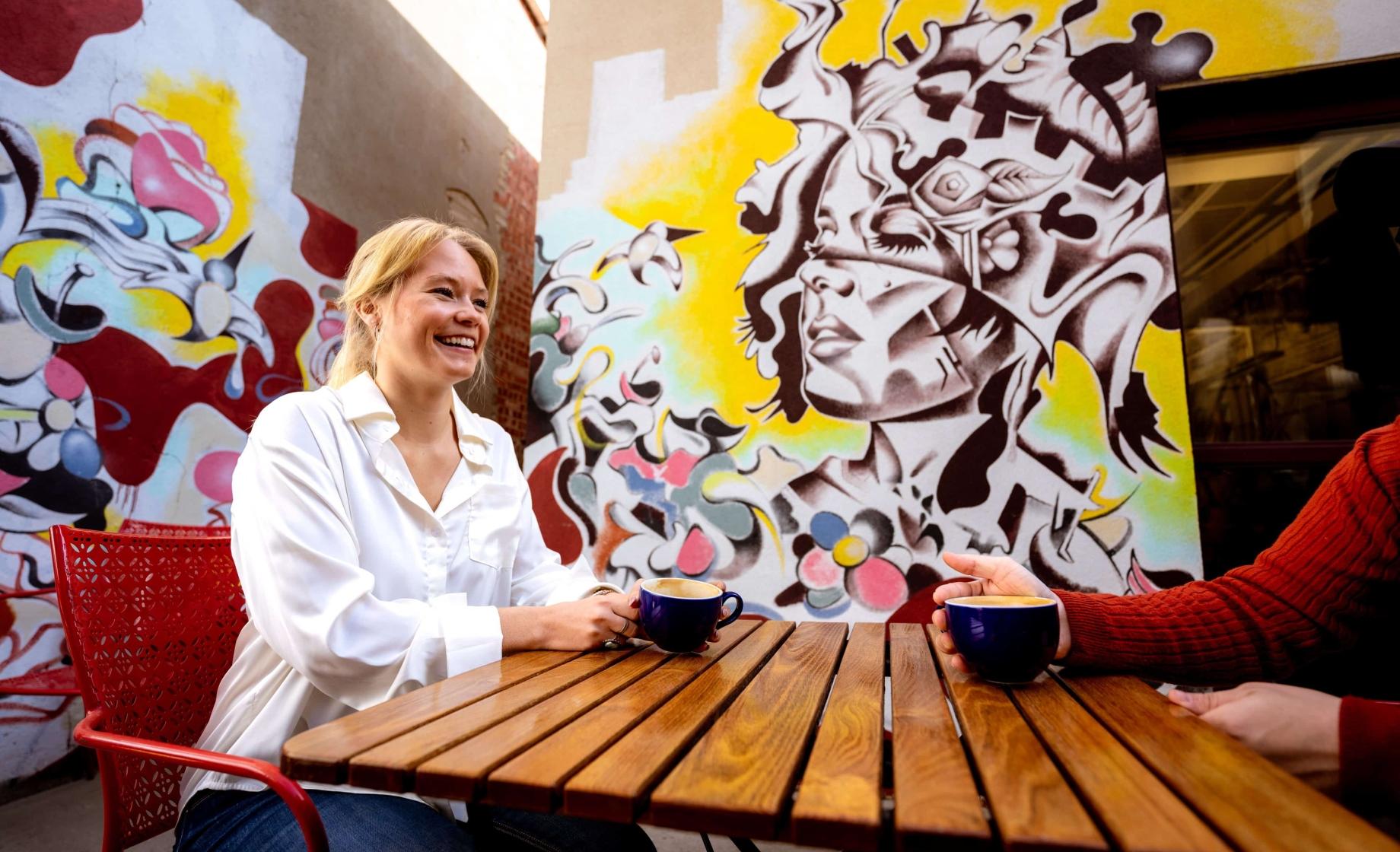 A person enjoys coffee in front of art in the patio area of M.B. Haskett Delicatessen in Sioux Falls