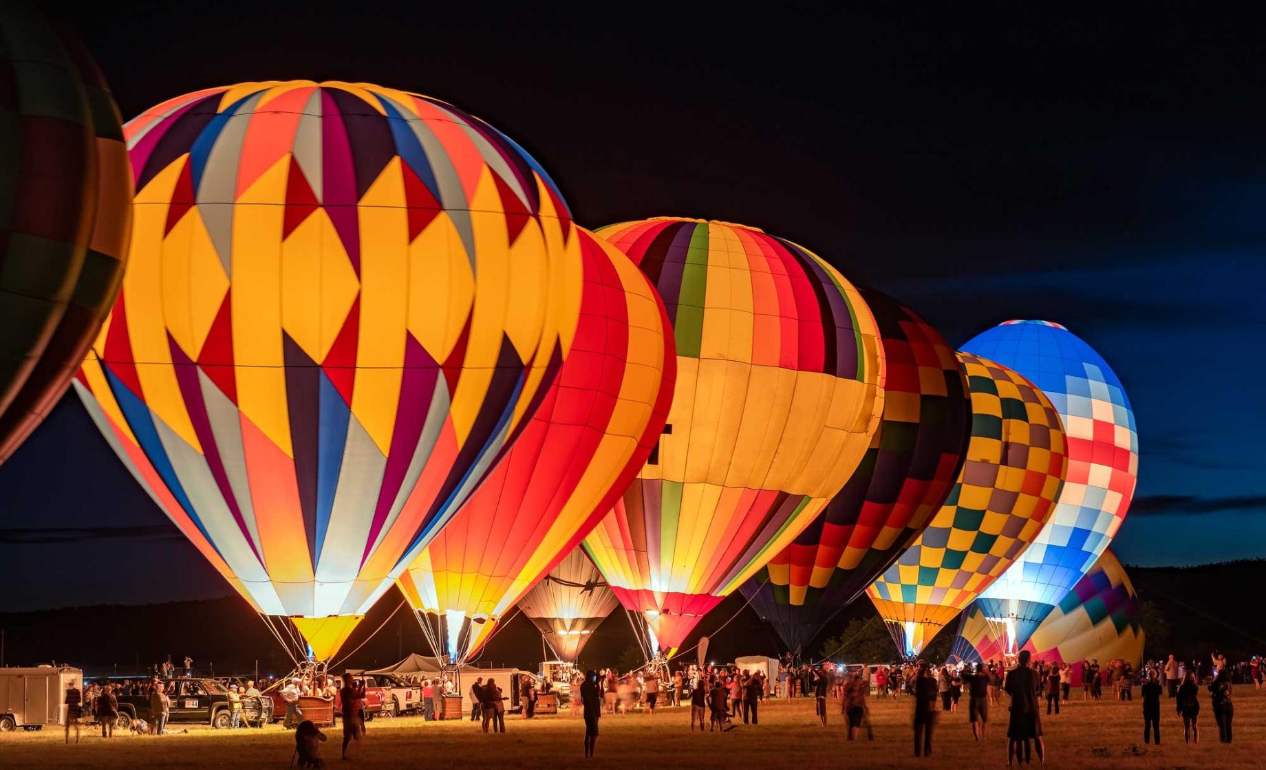 Row of inflated and glowing hot air ballons at dusk