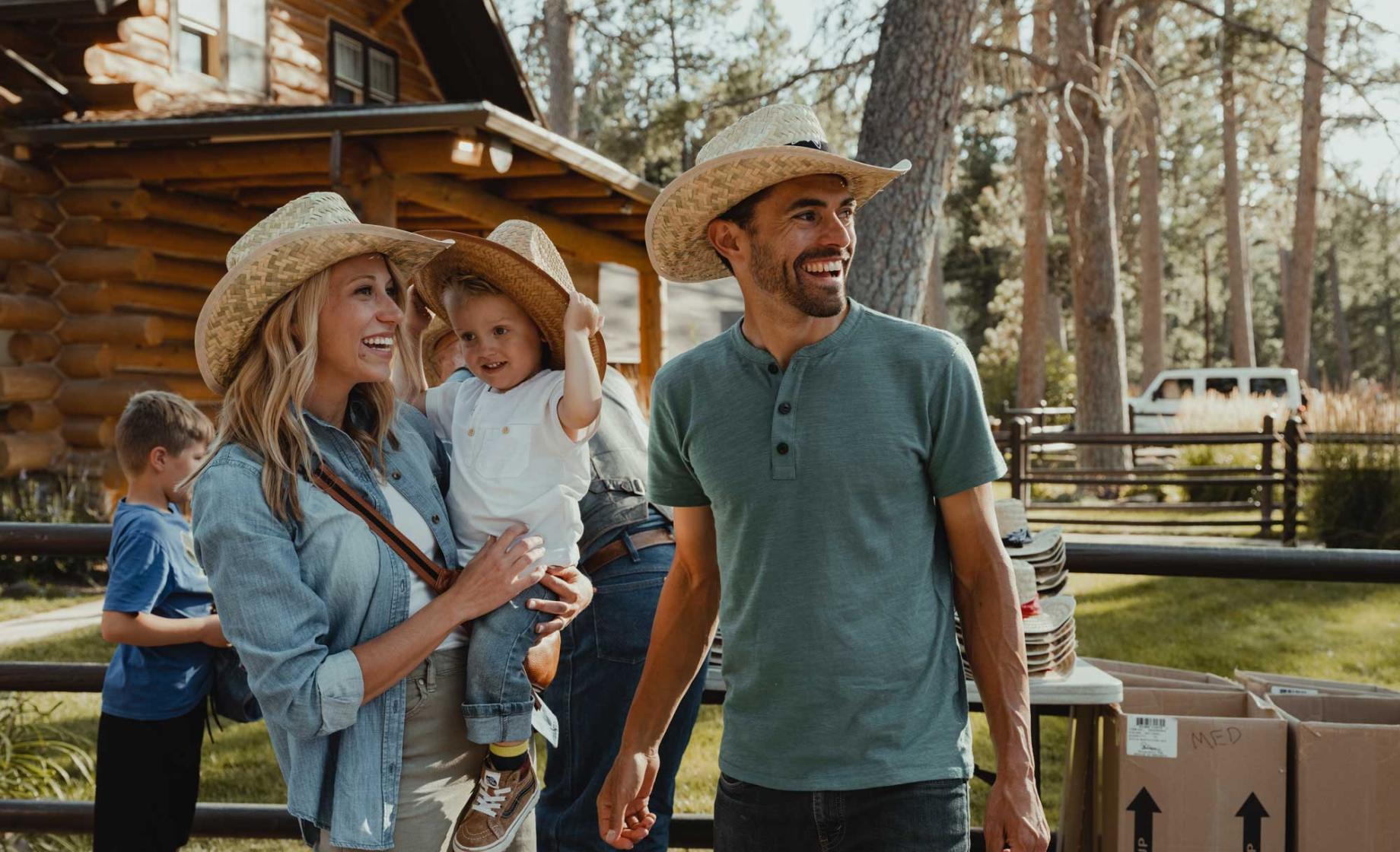 family with cowboy hats standing near a cabin