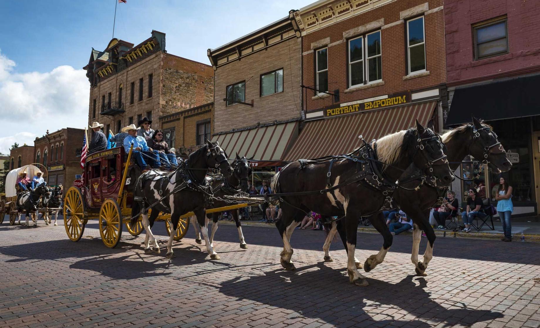 Horse-drawn wagons proceed down Main Street during the Days of '76 Rodeo & Parades. Deadwood, South Dakota.