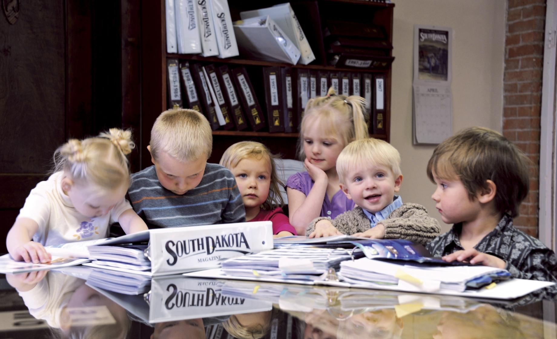 Kids gather around to look at South Dakota Magazine