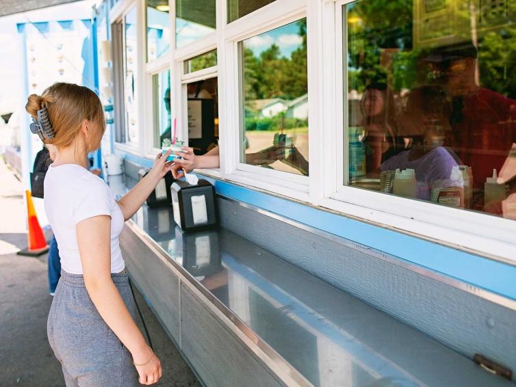 Teen girl taking ice cream from a service window at Subzero