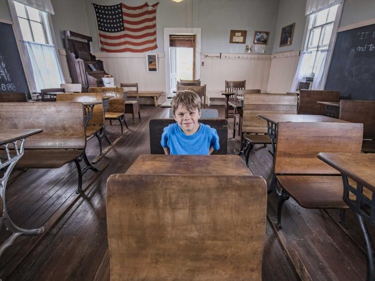 Boy sitting at a desk inside the Laura Ingalls Wilder Schoolhouse