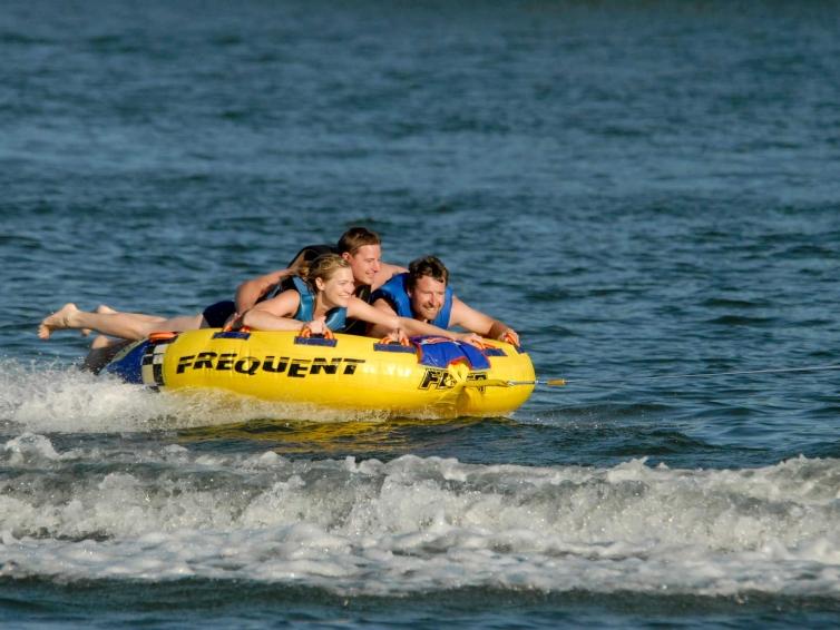 A family of three enjoys riding a large yellow innertube through the water on Lake Kampeska in Watertown.