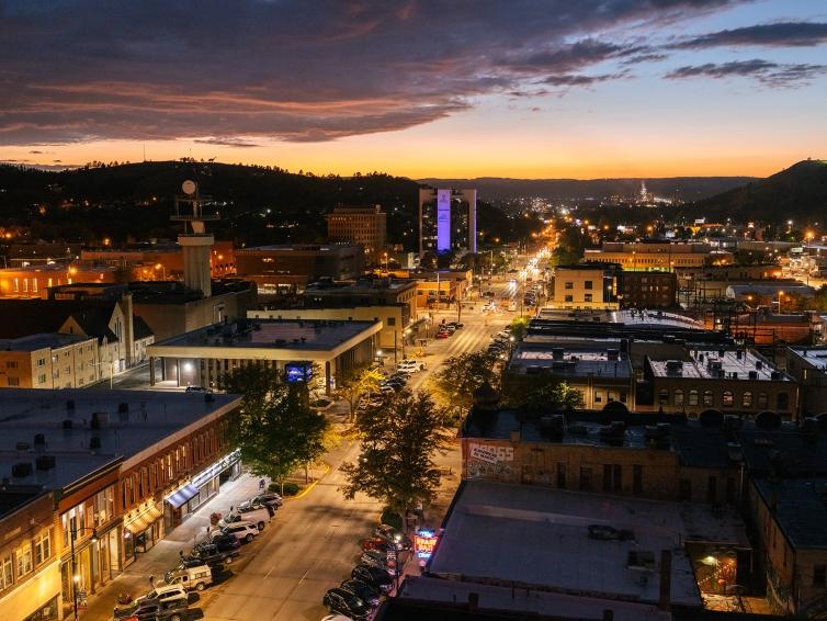 An aerial view of Rapid City at night, lit by warm streetlights and vehicle headlights.