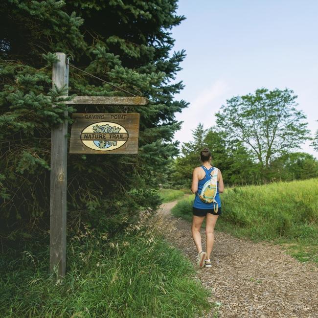 Woman walking next to Gavins Nature Trail sign