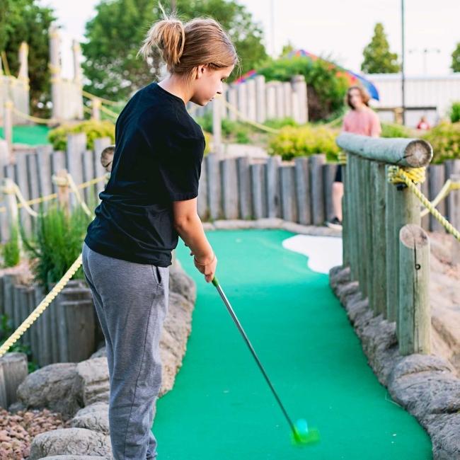 Young teen girl playing mini golf