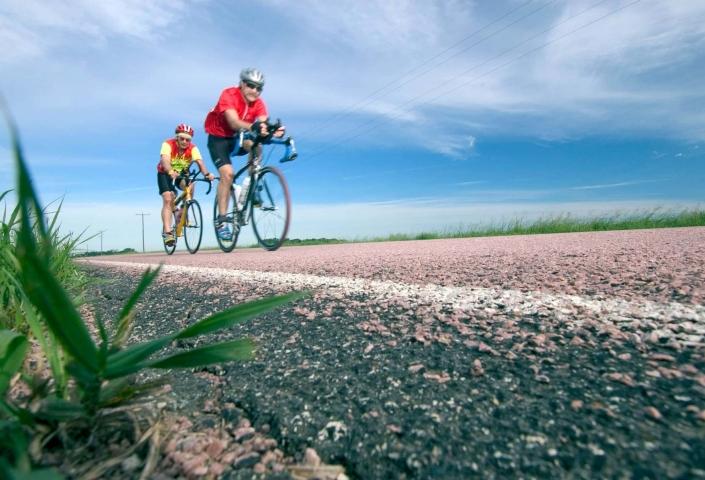 Two men road biking with a blue sky background