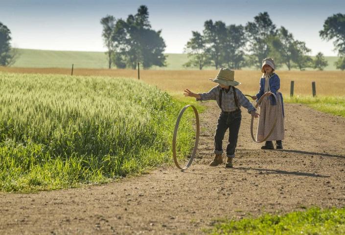 two kids dressed in period clothing playing with hoops