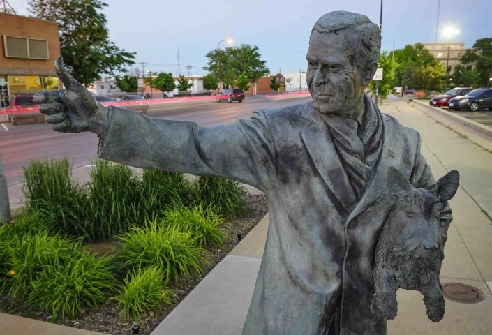 A statue of George W Bush extends a thumbs up while holding a dog in downtown Rapid City