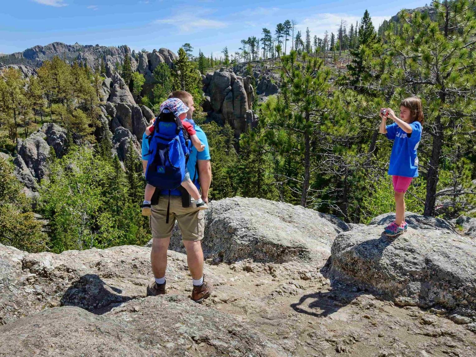 Little girl taking a picture of dad and toddler