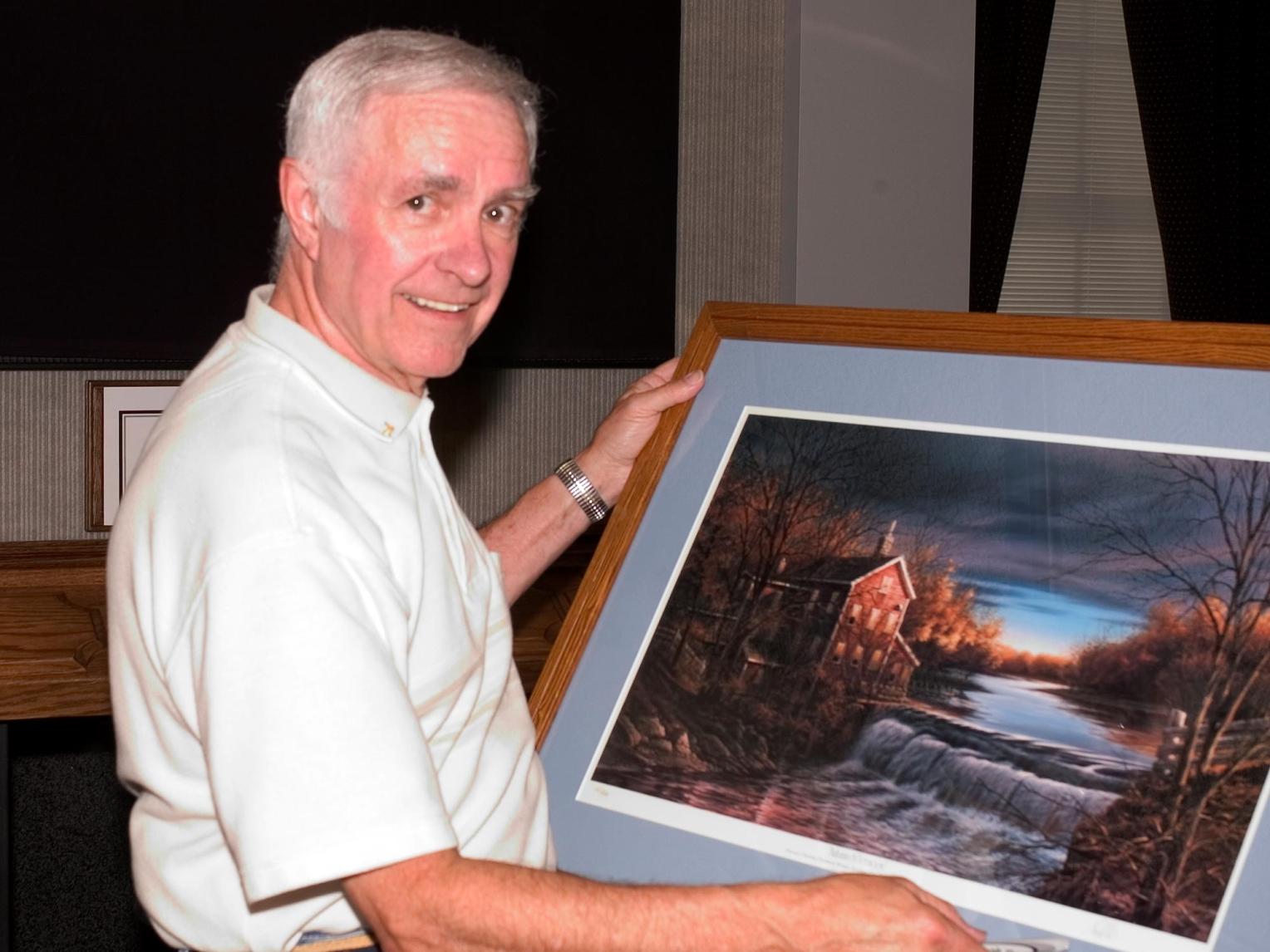 Terry Redlin holding a framed painting
