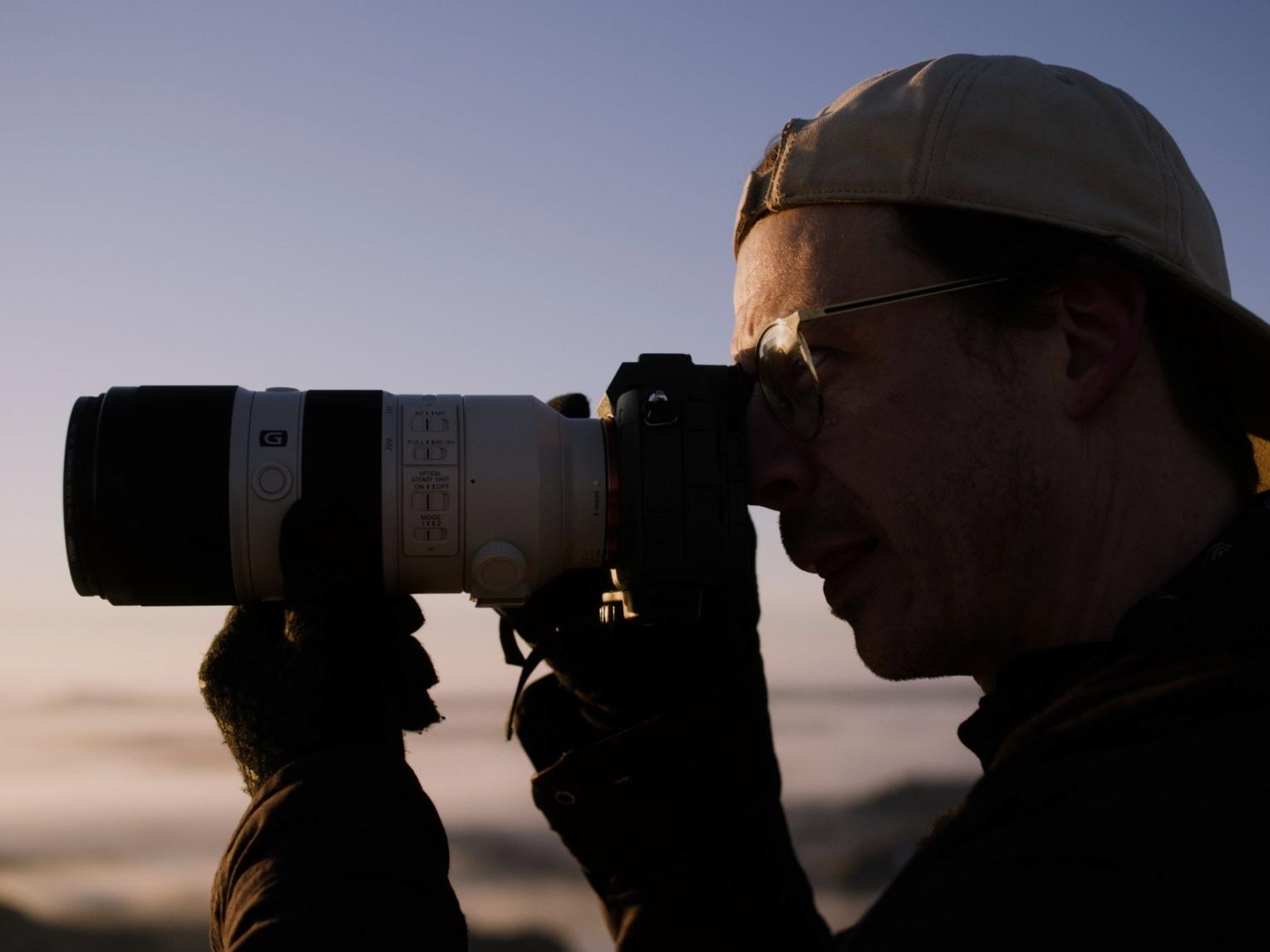 Wes Eisenhauer adjusts the lens on his camera as he prepares to shoot a photo in Badlands National Park