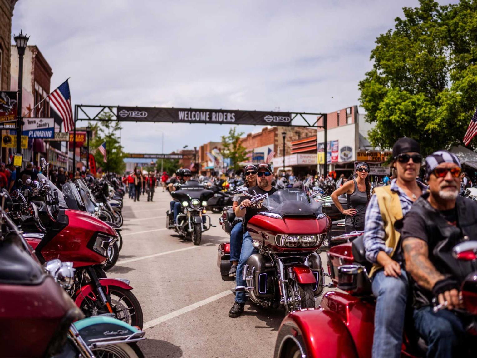 Bikers ride down a street lined with motorcycles in downtown Sturgis, South Dakota, during the Sturgis Motorcycle Rally.