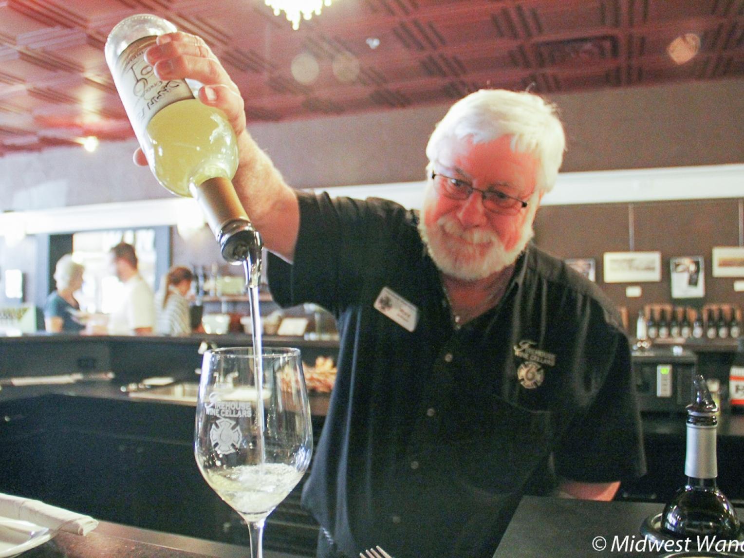 A staff member at Firehouse Wine Cellars pours a glass of wine.