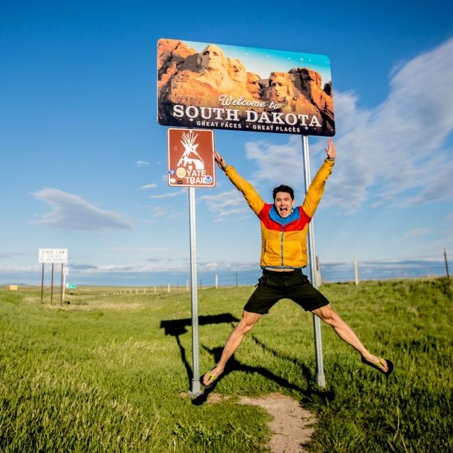 Jumping in front of the Welcome to South Dakota sign
