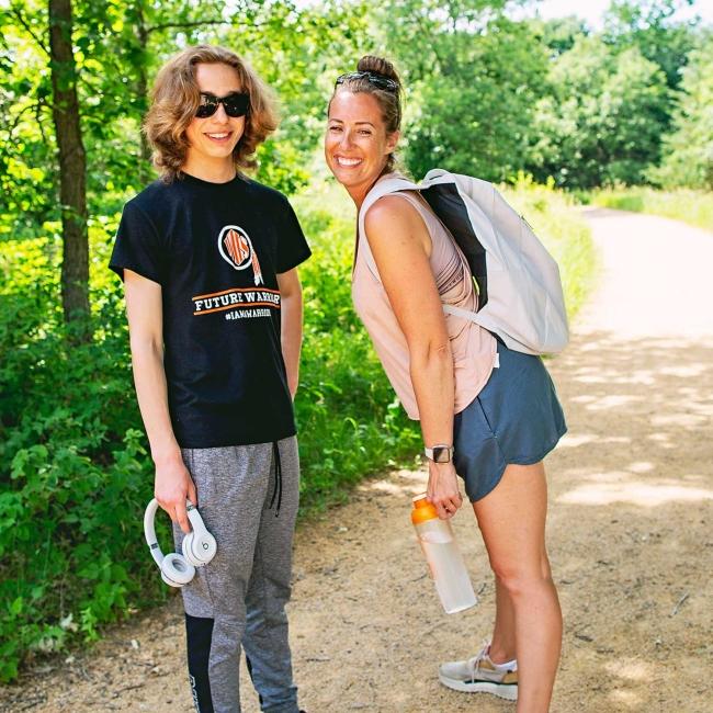 Mom and son smiling at the camera in activewear on a hike