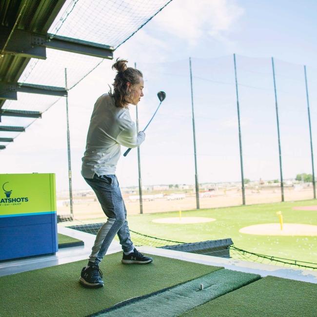 Teen boy swinging a golf club at Great Shots